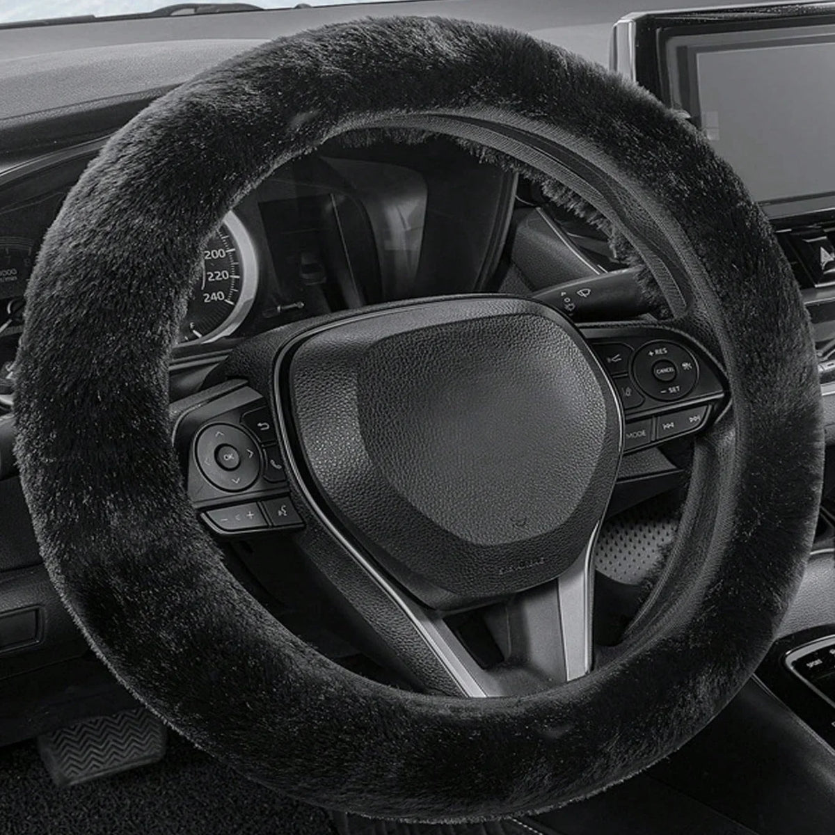 A close-up view of a black winter plush steering wheel cover inside a car's interior.