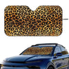 A leopard print car sunshade placed on the front window of a blue car.