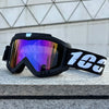 Black windproof sports goggles with iridescent purple and blue lenses resting on a gray stone surface.