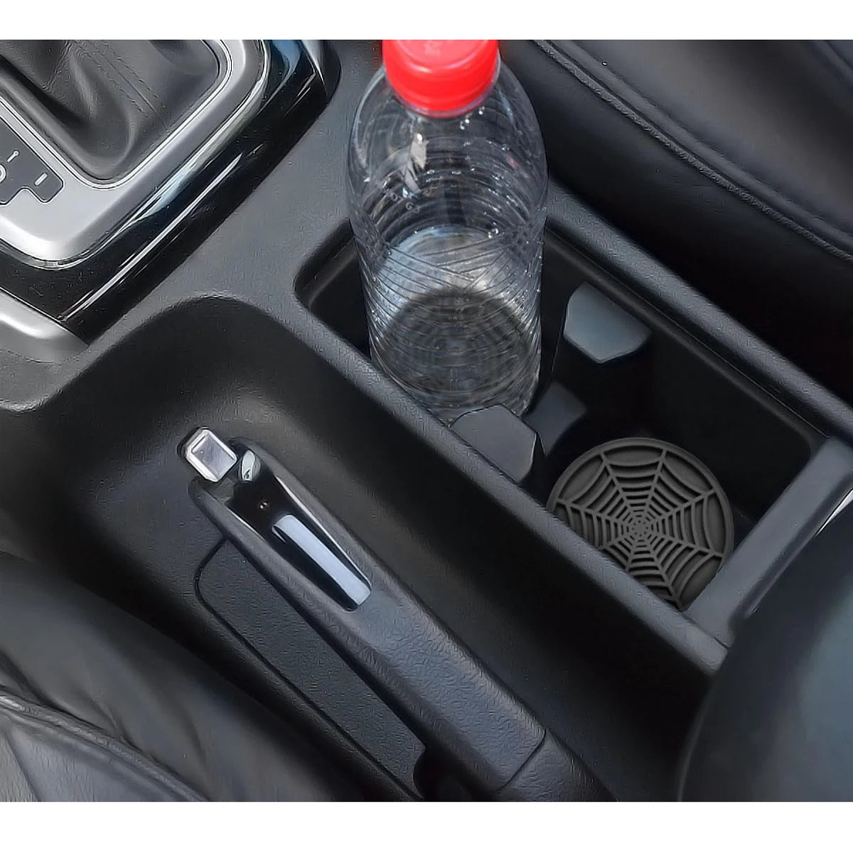 A clear plastic bottle and a silicone spider web coaster are shown in a car console.