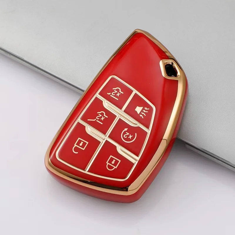 A red multi-function car key cover with gold accents shown on a gray surface.