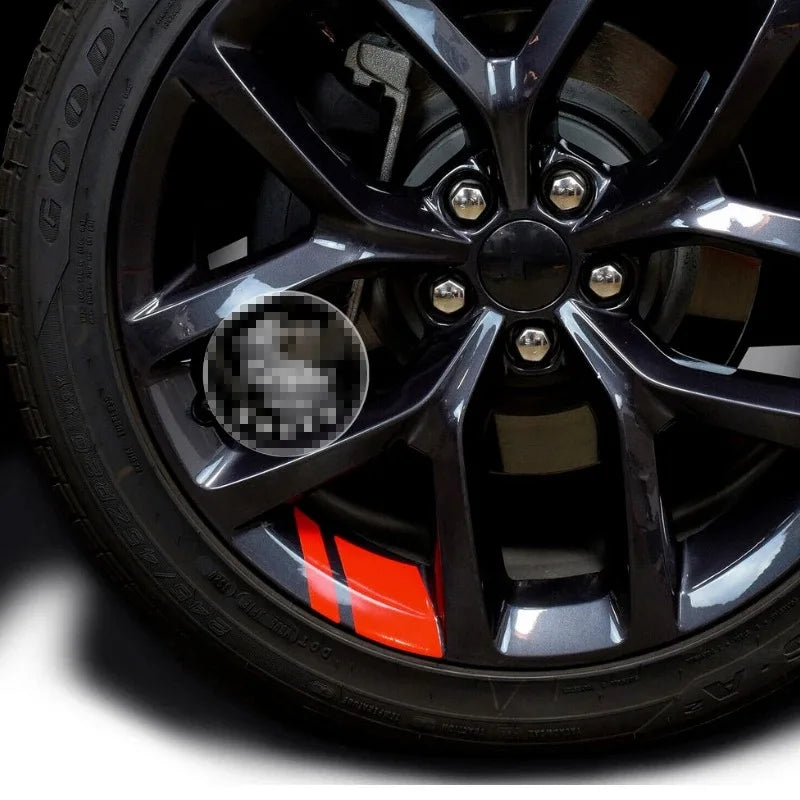 Primer plano de una rueda automotriz negra con acabado oscuro y pegatinas en el cubo.