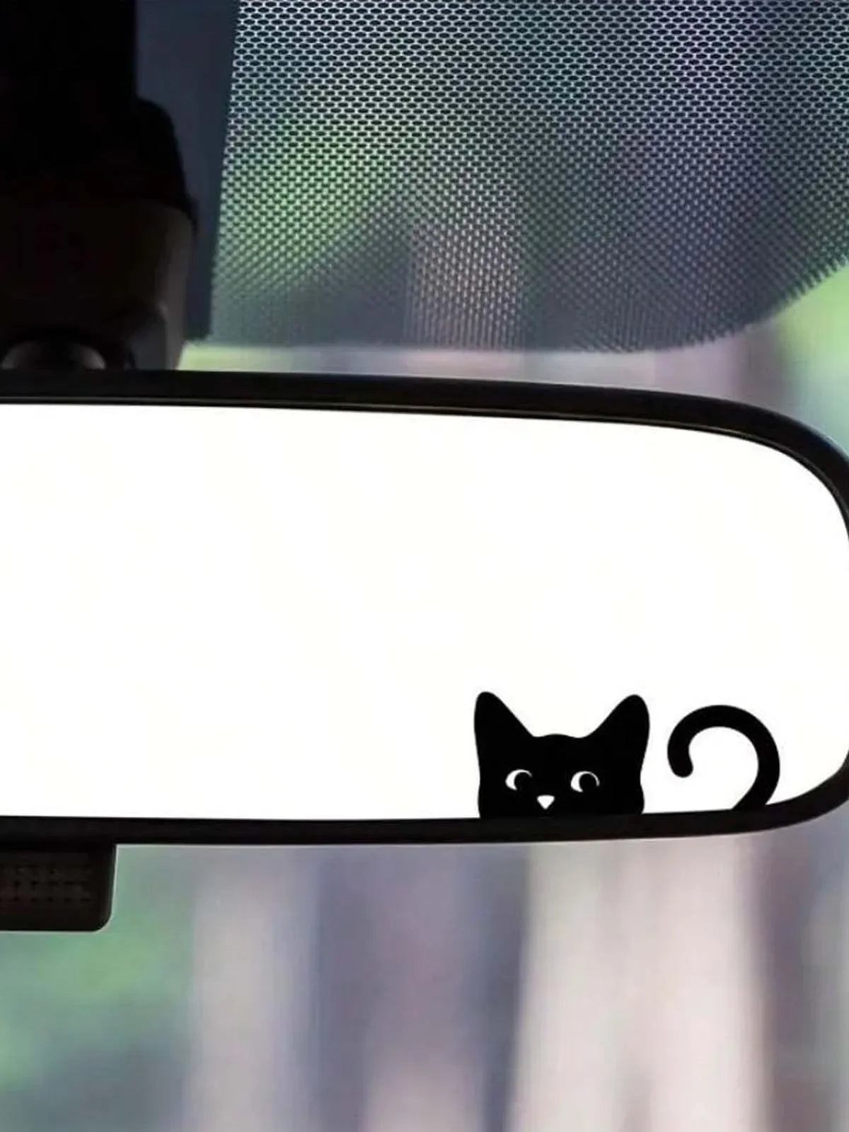 A close-up of a cat decal placed on a rearview mirror, showing a black silhouette of a cat against a white background.
