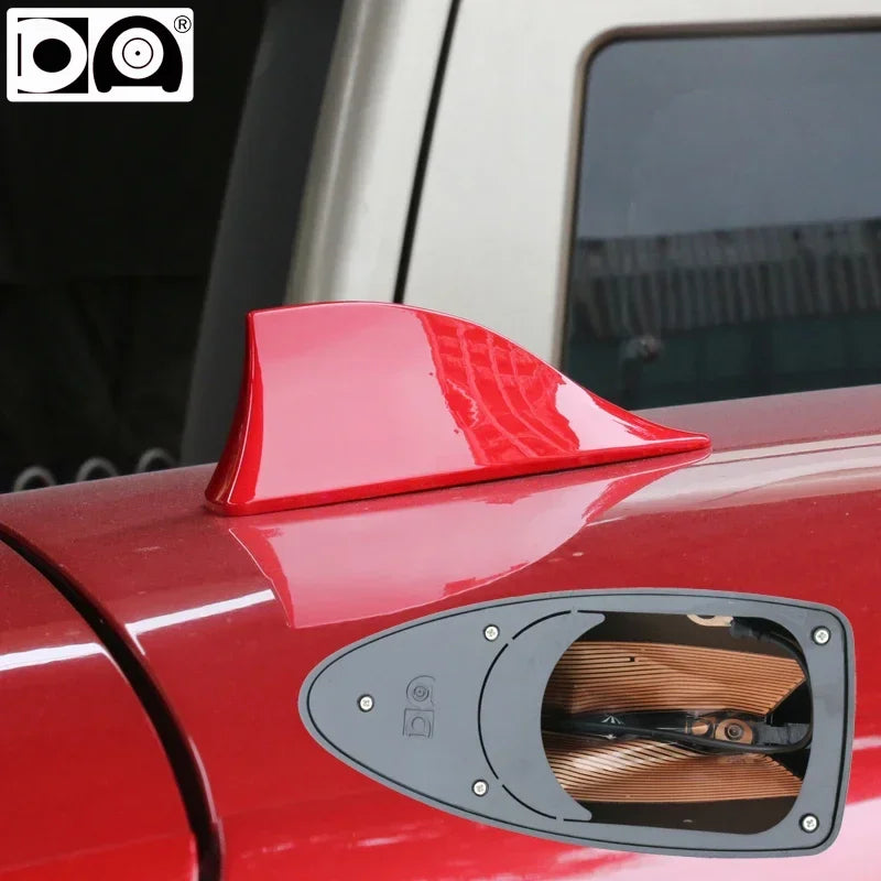 Gros plan du toit d'une voiture rouge avec une antenne à nageoire de requin noire montée dessus.