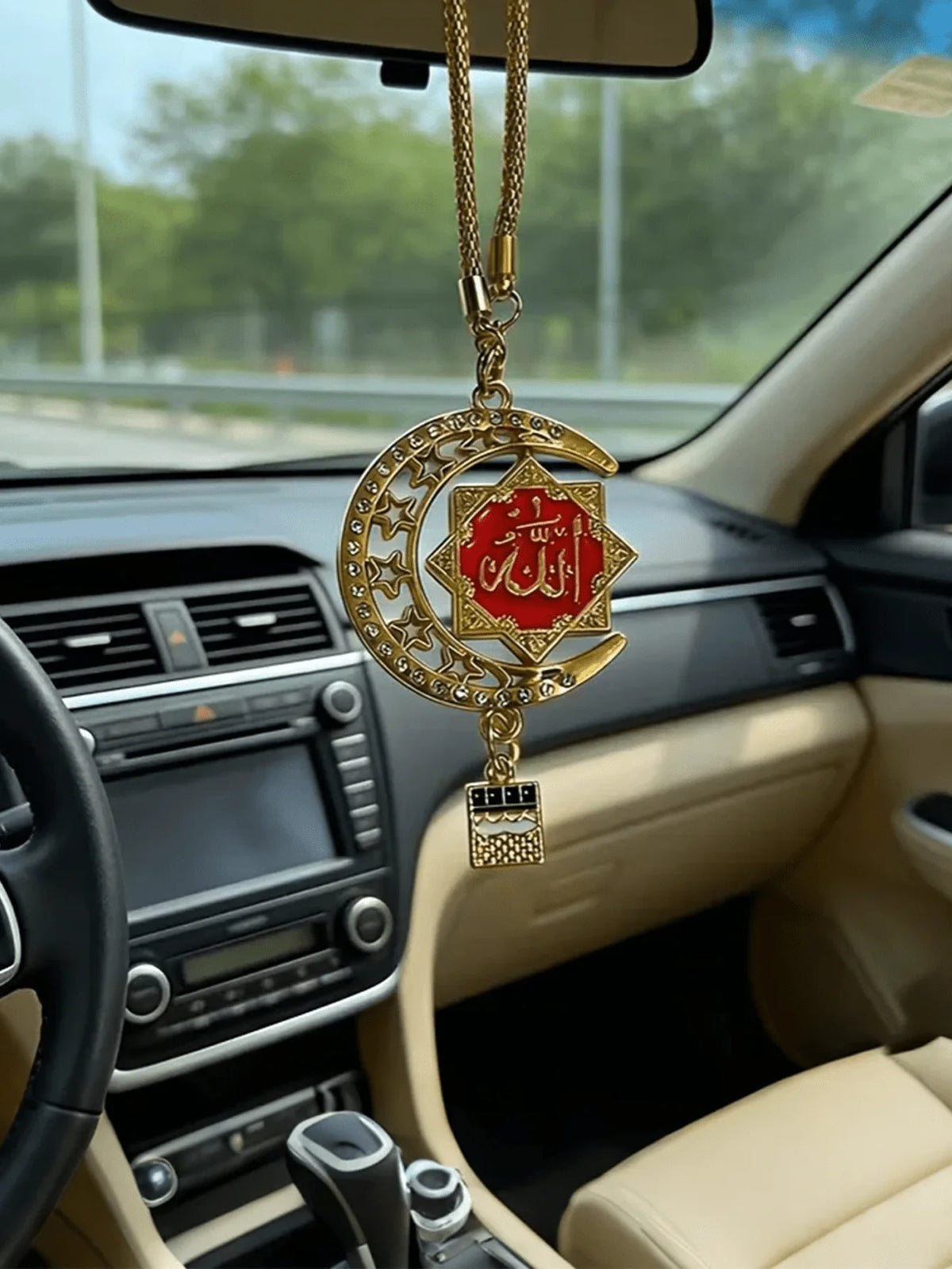 Goldene islamische Kalligrafie-Anhänger hängt an einer Kette in einem Autoschaltfeld.