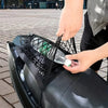 A hand is placing a green bottle into a black high-stretch double-layer motorcycle cargo net with hooks.