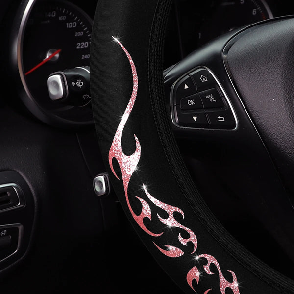 A close-up of a black steering wheel cover featuring a shimmering pink flame design.