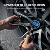 A hand is using a digital tire pressure gauge with an inflator and quick connect coupler to measure tire pressure.