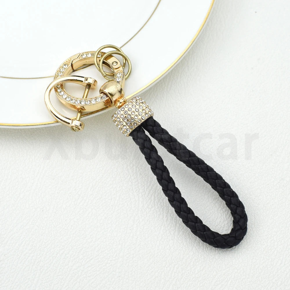 Gold- und diamantbesetztes Schlüsselanhänger-Halter mit schwarzem Kabel auf weißem Hintergrund