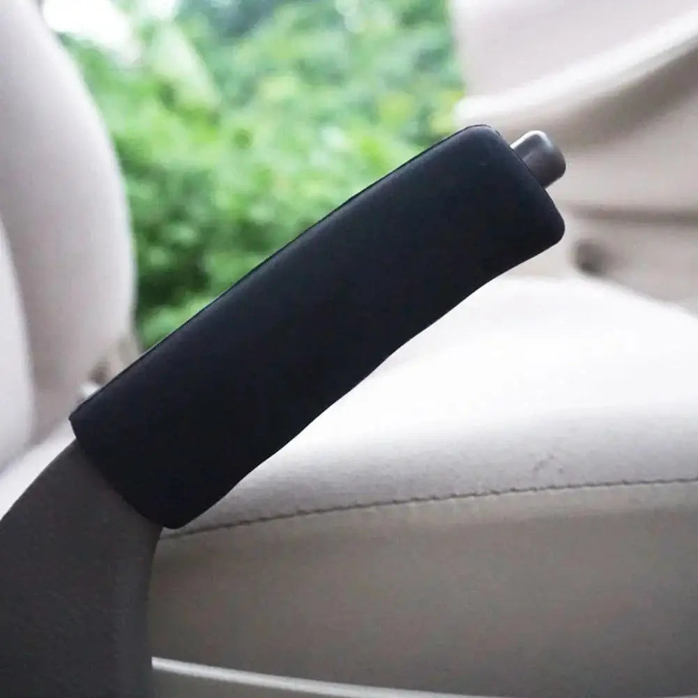 A black car gear shift knob and handbrake cover set is shown on a light-colored vehicle interior.