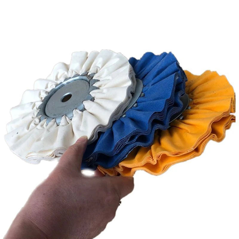 A hand is holding a professional mill treated airway buffing wheel with white, blue, and orange fibers.