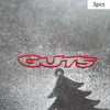 Three red vinyl decals spelling out GUTS reflected on a wet surface.