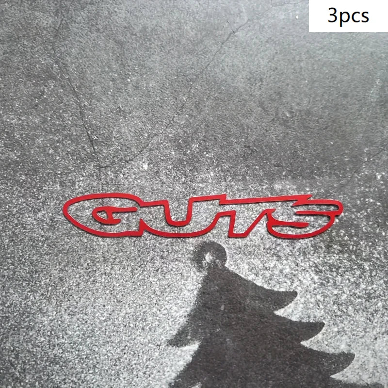 Three red vinyl decals spelling out GUTS reflected on a wet surface.