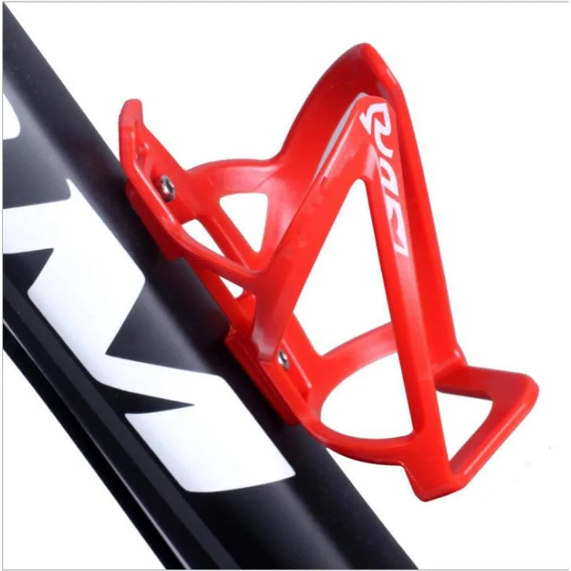 A red plastic bicycle bottle holder rack is shown mounted on a black bicycle frame.