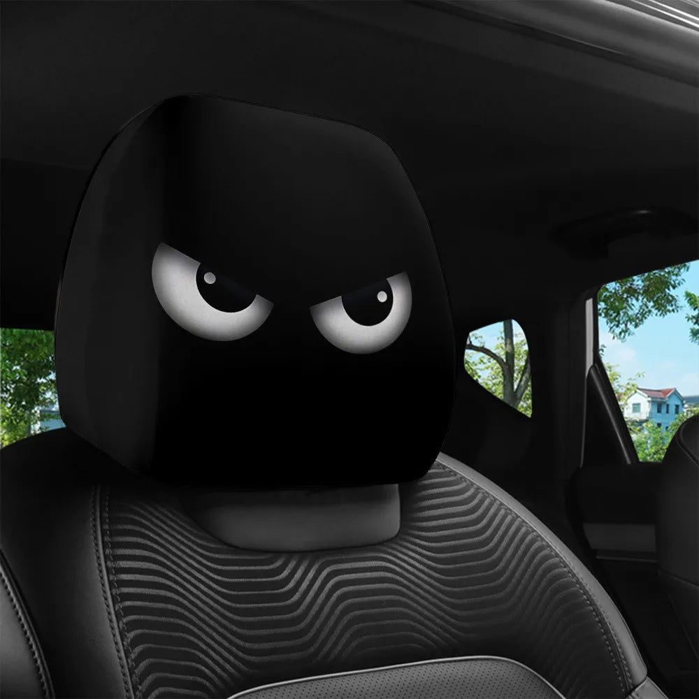 A close-up view of a black car headrest cover with slanted eyes, placed on a black car seat.