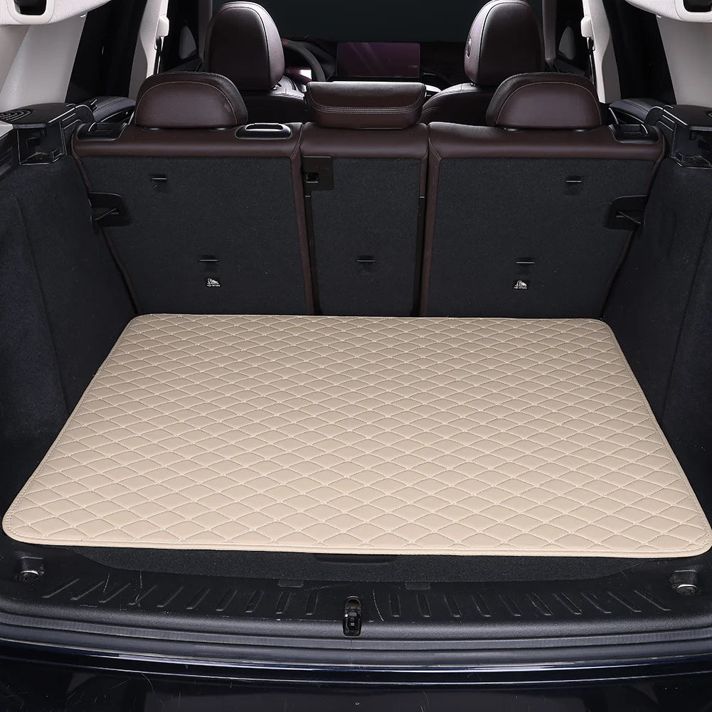 A beige rhombus pattern car trunk mat is shown inside a vehicle trunk with dark leather seats visible.