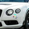 Close-up of a white car's headlight assembly with a reflective 5-point star decal applied to the front bumper.