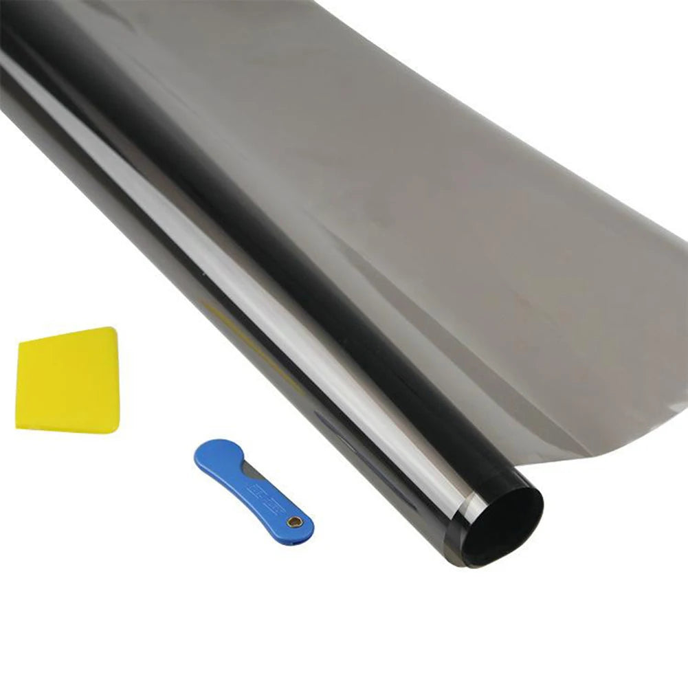 A close-up view of a rolled, reflective car window tint film and a yellow tool.