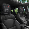 Two black faux leather car headrest covers with slanted red eyes installed in a vehicle interior.