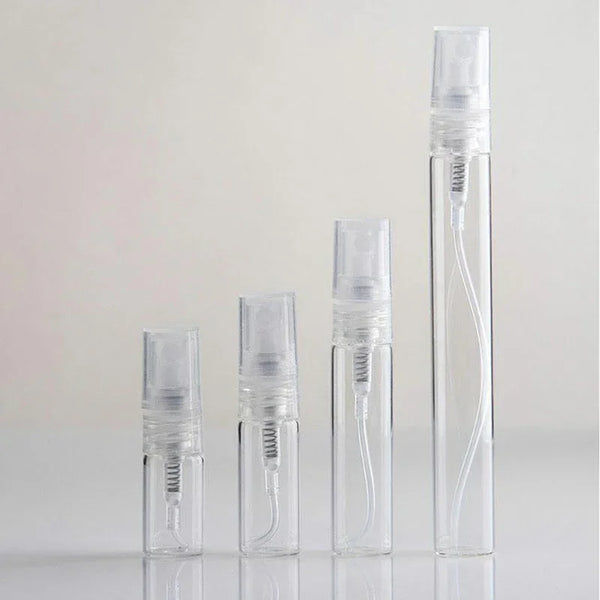 Un set de botellas de perfume de vidrio transparente con goteros de color plateado y líquido dentro.