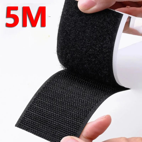 A hand is holding a black hook and loop tape strip for organization and DIY.