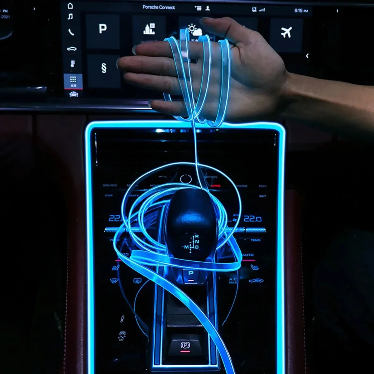 A hand is connecting a flexible blue LED light strip to a car interior display screen.