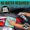 Une main essuie l'extérieur d'une voiture avec un chiffon vert, démontrant un nettoyage chimique sans eau pour véhicules.