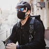 A person wearing a black jacket and mask holds a heavy-duty retractable keychain badge holder with a carabiner.