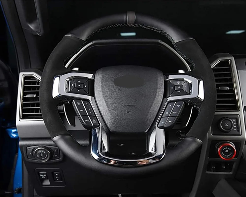 Close-up view of a black steering wheel with silver trim and controls inside a vehicle