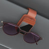 A pair of dark purple sunglasses resting in a rose gold clip holder against a gray background.