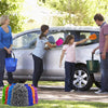 Three people washing a silver car with a double-sided microfiber mitt and various colored sponges in a yard.