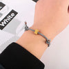 A hand is wearing a black and white twisted bracelet, likely a heart-shaped fitness tracker.