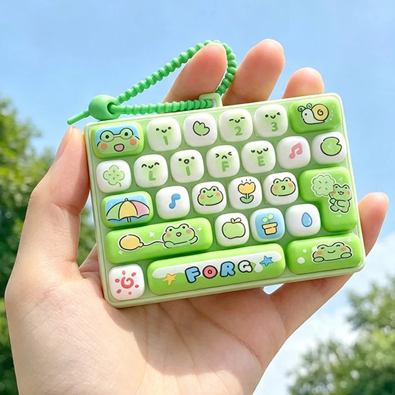 A hand holds a green keycap stress relief button set with various cartoon-themed buttons and a green cord.