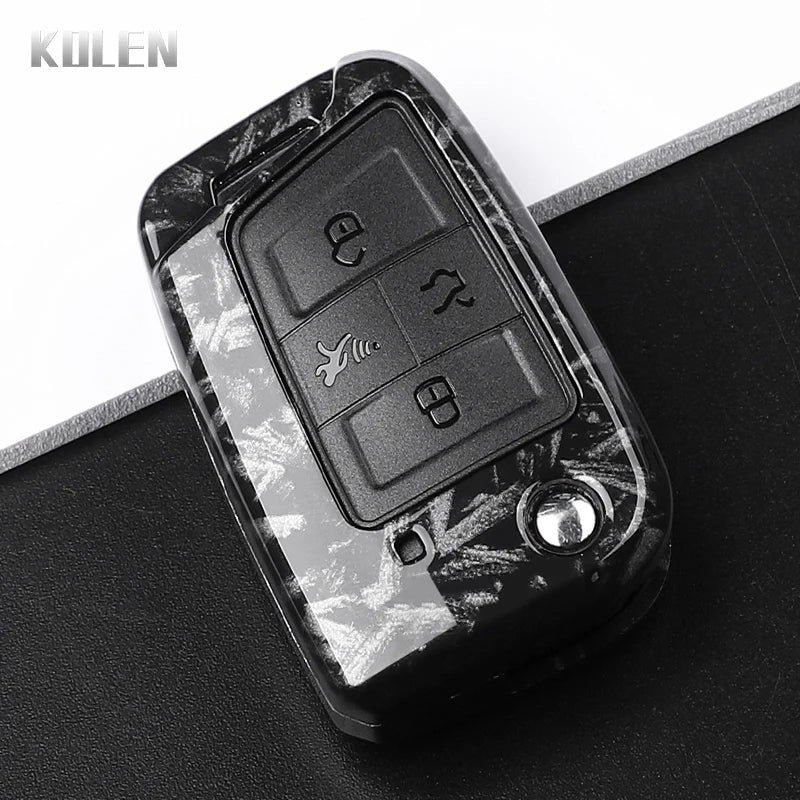 A black carbon fiber button cover for a car key, showing various buttons and a logo.
