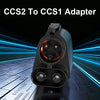 A black adapter for converting CCS2 to CCS1 electric vehicle charging plugs, shown on a technical surface.