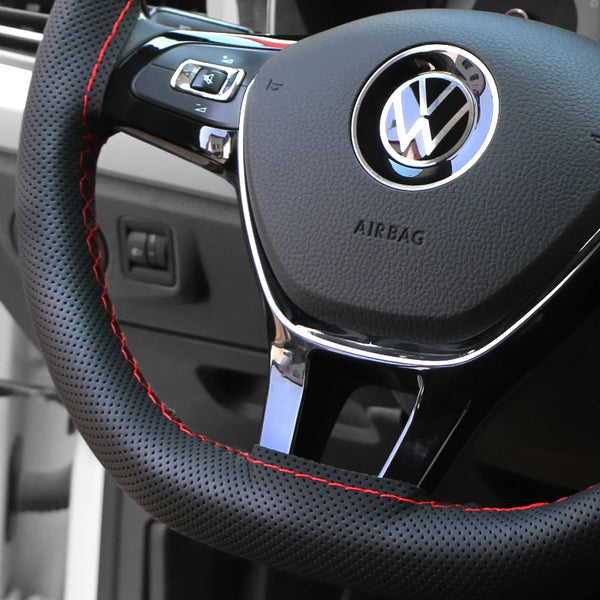Close-up of a black steering wheel cover with a silver Volkswagen logo and airbag text.