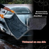 A black microfiber car drying towel is being used to wipe a car surface, highlighting its substantial area and thickness.