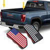Close-up of truck bed rail hole plugs, including an American flag and a black and white star pattern, shown near a blue picku