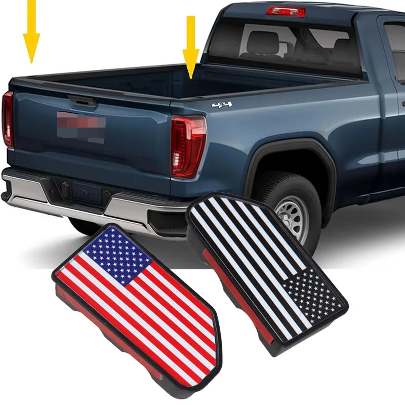 Close-up of truck bed rail hole plugs, including an American flag and a black and white star pattern, shown near a blue picku