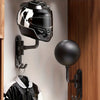 Un casque de moto noir est exposé sur un crochet mural à côté d'un luminaire rond noir.