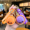 A hand holds several cute bao bun silicone keychains in orange and purple colors.