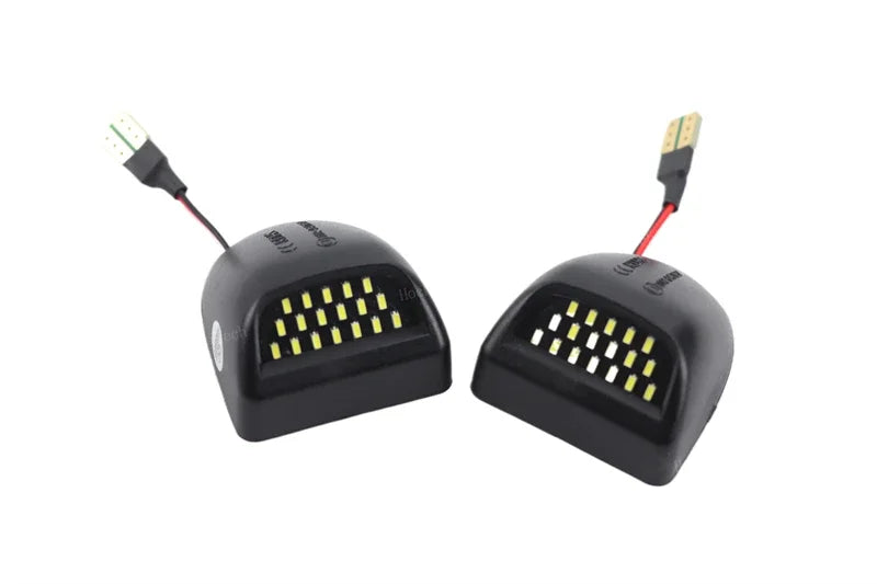 Un par de luces de matrícula LED de alta intensidad con carcasas negras y conectores eléctricos.