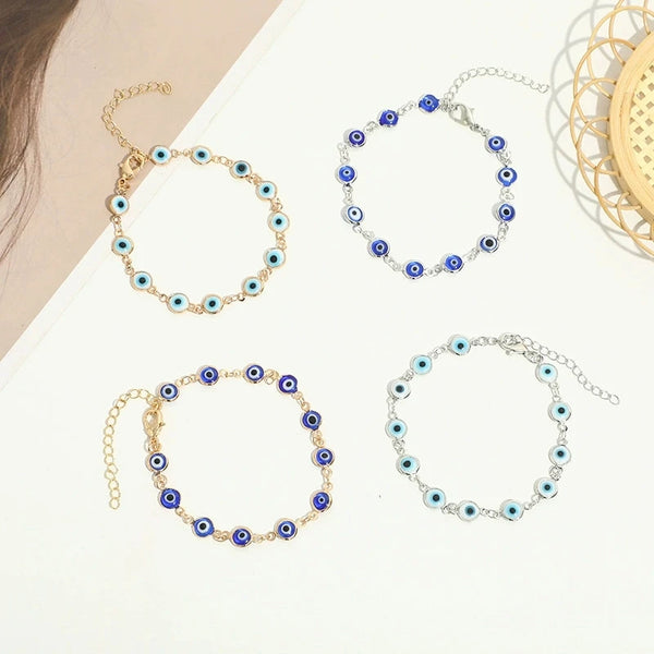 Three gold-plated evil eye charm bracelets with blue and white stones displayed on a white background.