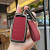A hand holds a maroon zinc alloy car key case with a leather strap and metal clip.