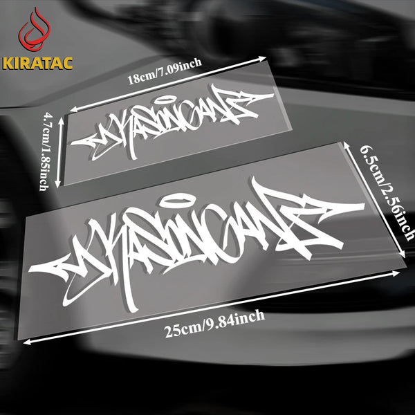 ملصقان فينيل أسود يحملان فن الجرافيتي (Wildstyle) أبيض على سطح مركبة داكنة.