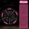 A close-up view of a black car tire and wheel with pink LED reflective decoration.