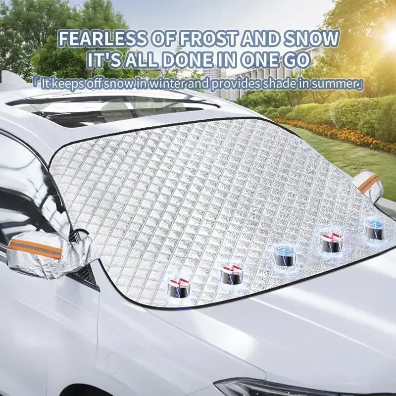 A clear plastic windshield sunshade and snow protector is installed on a silver car windshield.