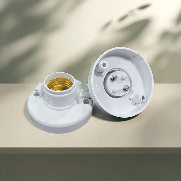 A white E27 screw cap light bulb holder with a gold-colored bulb visible inside, resting on a light surface.