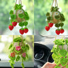 A hand holds a strawberry crochet hanging car decor made of green yarn and pink flowers.