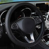 Close-up view of a black leather steering wheel cover inside a car interior.